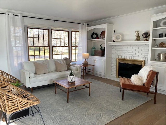 living room featuring ornamental molding, wood finished floors, built in shelves, and a brick fireplace