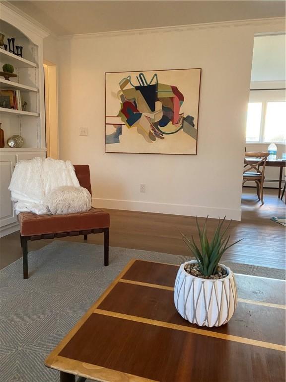 living room with wood finished floors, ornamental molding, built in features, and baseboards