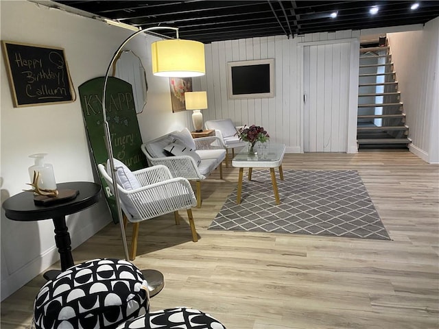 living area with baseboards, stairway, and wood finished floors