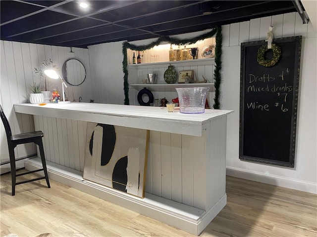 bar area featuring wood finished floors, wood walls, and a baseboard heating unit