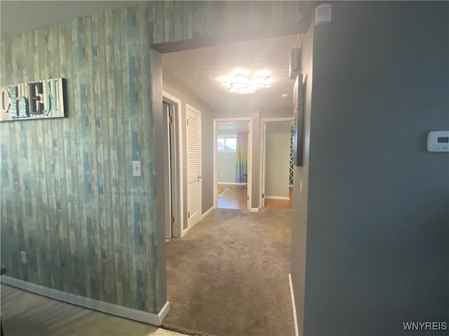 corridor featuring baseboards and carpet flooring