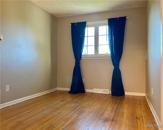 empty room with hardwood / wood-style floors and baseboards