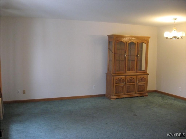empty room featuring carpet floors, a chandelier, and baseboards