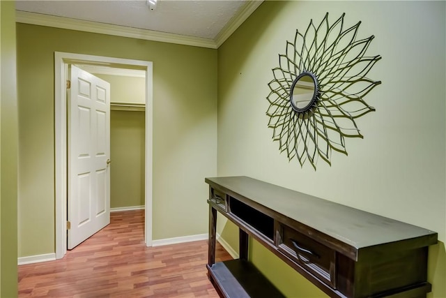 hallway with wood finished floors, ornamental molding, and baseboards