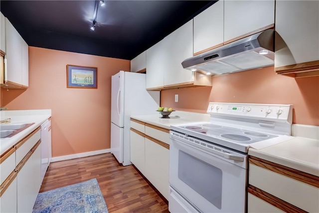 kitchen with under cabinet range hood, white appliances, light wood-type flooring, white cabinetry, and light countertops