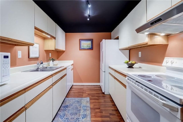 kitchen featuring white appliances, under cabinet range hood, a sink, wood finished floors, and light countertops