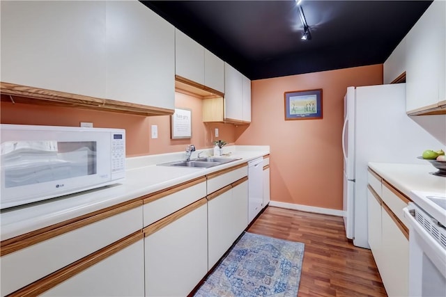 kitchen featuring white appliances, light wood-style floors, white cabinets, light countertops, and a sink
