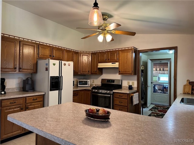 kitchen with stainless steel range with gas stovetop, white refrigerator with ice dispenser, ceiling fan, under cabinet range hood, and a peninsula