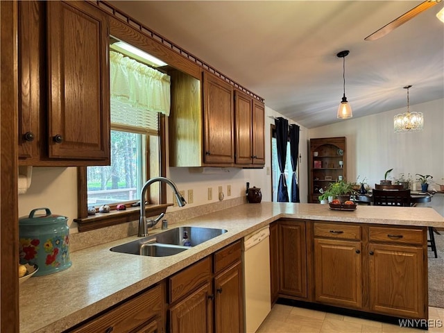 kitchen featuring a sink, white dishwasher, a peninsula, brown cabinetry, and light countertops