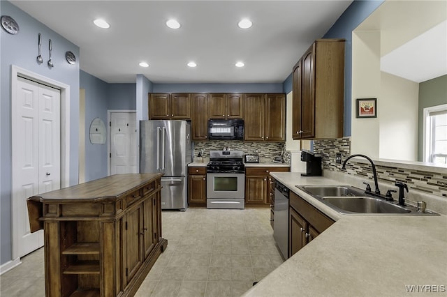 kitchen with appliances with stainless steel finishes, a sink, decorative backsplash, recessed lighting, and light tile patterned floors