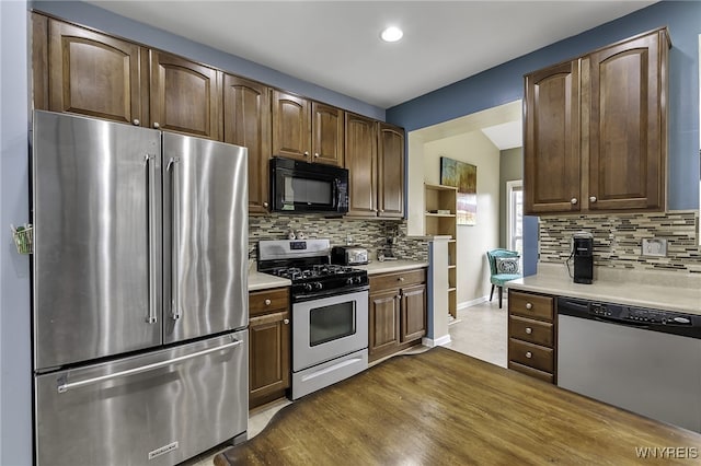 kitchen with appliances with stainless steel finishes, light countertops, tasteful backsplash, and recessed lighting