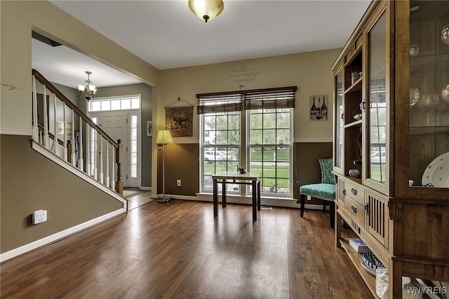 doorway with baseboards, a chandelier, stairs, and wood finished floors
