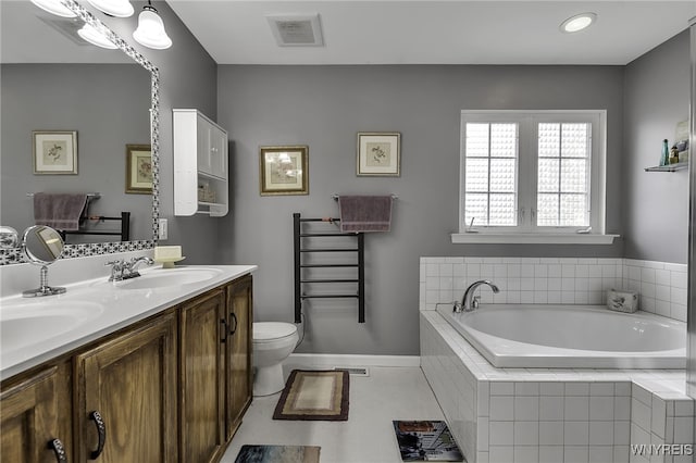 full bathroom featuring a garden tub, baseboards, double vanity, and toilet
