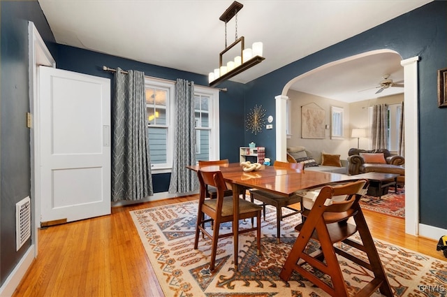 dining space featuring arched walkways, light wood-style flooring, baseboards, and ceiling fan