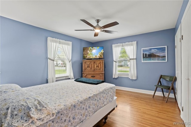 bedroom featuring baseboards, light wood-style flooring, and ceiling fan