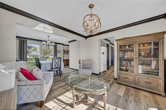 living area with a chandelier, ornamental molding, and wood finished floors