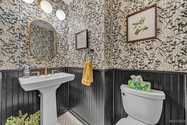 bathroom featuring wallpapered walls, wainscoting, toilet, and tile patterned flooring