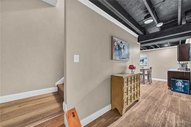 hallway featuring light wood-style floors, baseboards, and stairs