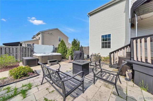 view of patio / terrace with a hot tub, fence, and a fire pit