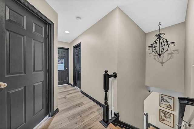 hall featuring an upstairs landing, light wood finished floors, a chandelier, baseboards, and recessed lighting