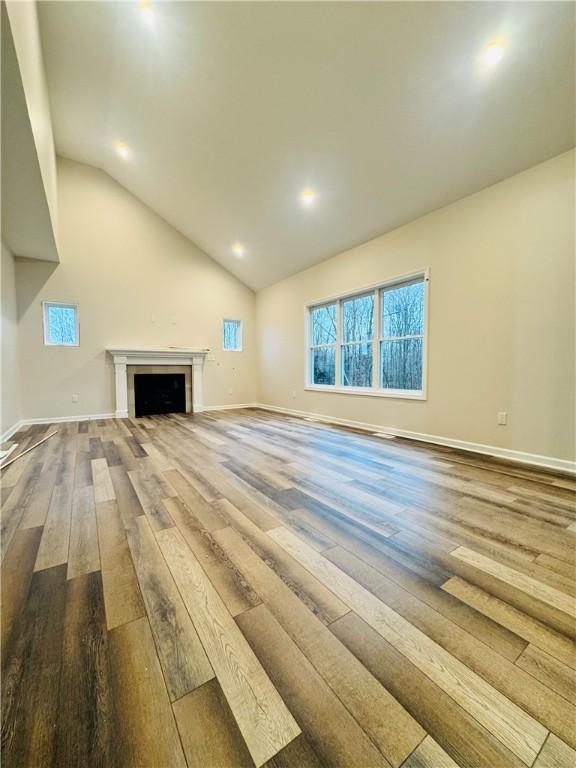 160 Jade Creek Dr, Greece, NY 14468 - unfurnished living room with wood-type flooring, vaulted ceiling, baseboards, recessed lighting, and a fireplace