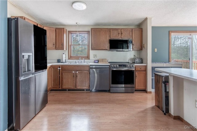 30204 County Route 179, Lyme, NY 13622 - kitchen featuring appliances with stainless steel finishes, a sink, light wood-type flooring, a textured ceiling, and light countertops