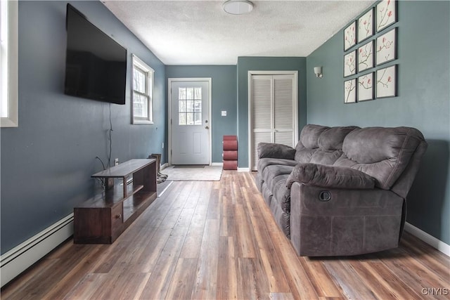 30204 County Route 179, Lyme, NY 13622 - living area featuring baseboard heating, a textured ceiling, wood finished floors, and baseboards