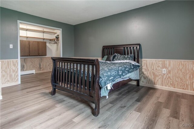 30204 County Route 179, Lyme, NY 13622 - bedroom featuring wood finished floors, a wainscoted wall, wooden walls, a walk in closet, and baseboards