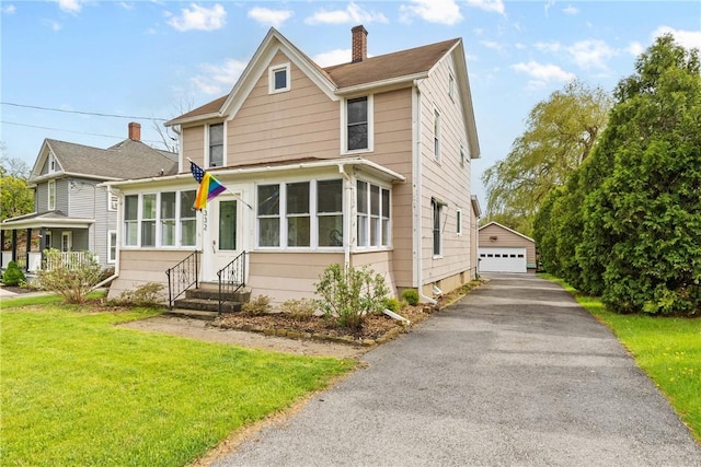 view of front of home with entry steps, a chimney, a garage, an outbuilding, and a front yard