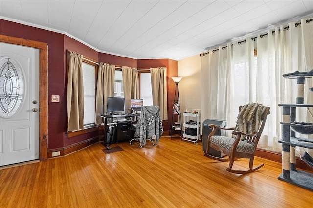 sitting room with wood finished floors, a desk, ornamental molding, and baseboards