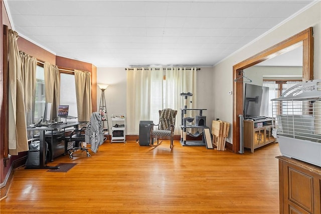 living area with ornamental molding, light wood-style floors, and an office area