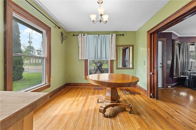 unfurnished dining area featuring plenty of natural light, baseboards, light wood-style flooring, and a chandelier