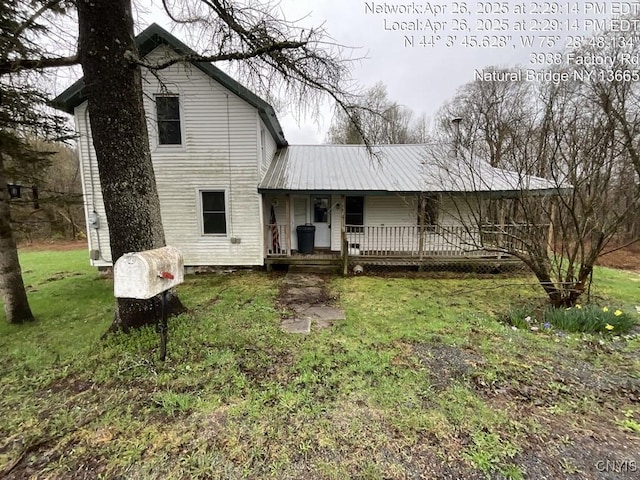 back of property featuring covered porch, metal roof, and a yard