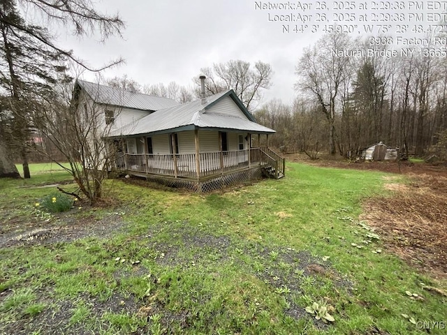 view of property exterior featuring covered porch, a yard, and metal roof