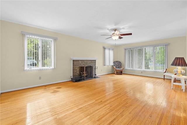 unfurnished living room featuring wood finished floors, plenty of natural light, ceiling fan, and a fireplace