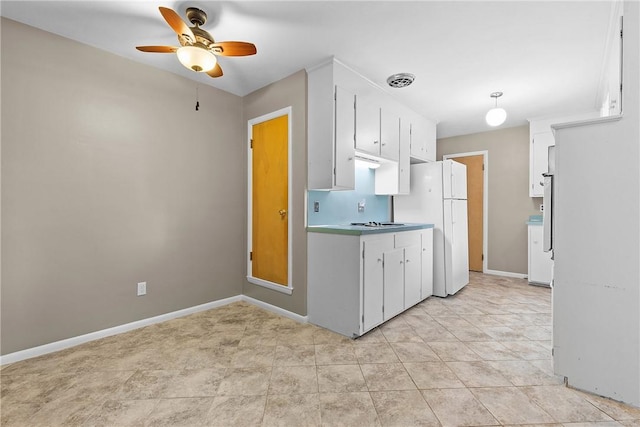 kitchen with freestanding refrigerator, white cabinets, a ceiling fan, baseboards, and cooktop