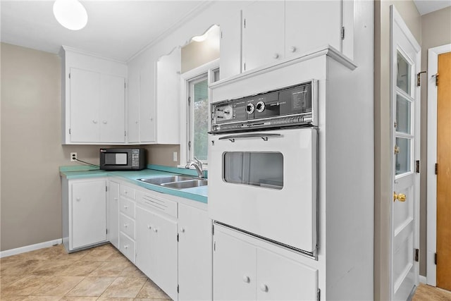 kitchen with white oven, a sink, white cabinetry, black microwave, and light countertops