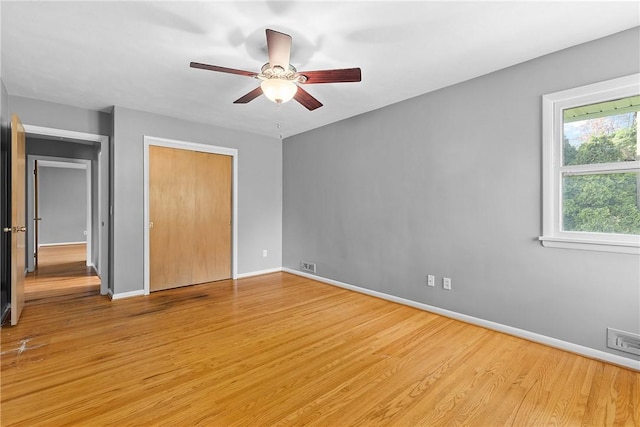 unfurnished bedroom featuring light wood-style flooring, baseboards, a closet, and a ceiling fan