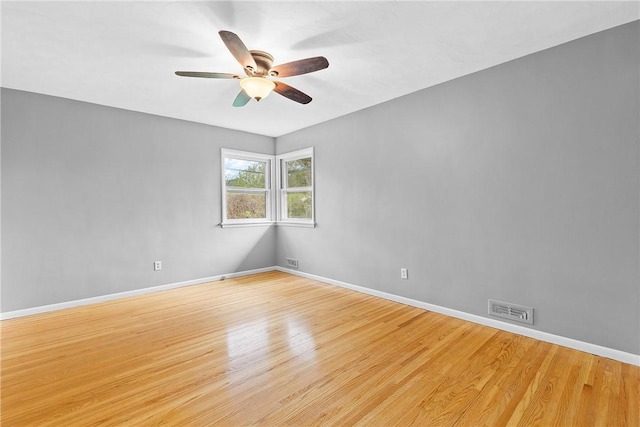 empty room featuring a ceiling fan, light wood finished floors, and baseboards