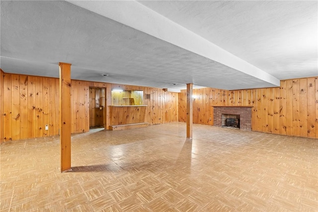finished basement featuring wood walls and a brick fireplace