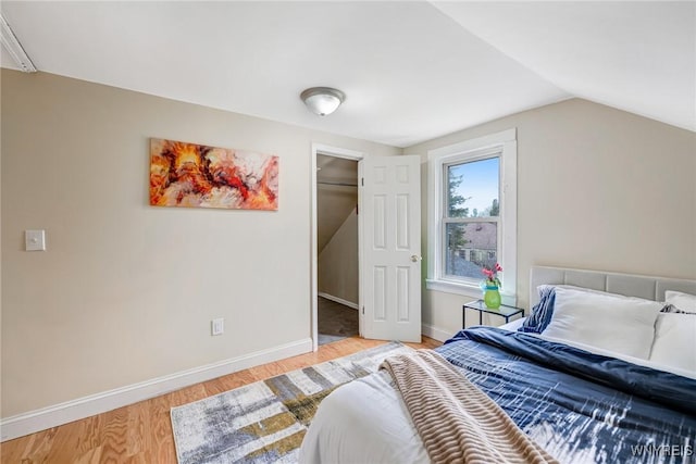 bedroom featuring lofted ceiling, light wood-style floors, and baseboards