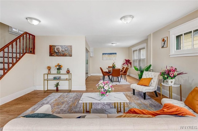 living room with stairs, wood finished floors, and baseboards