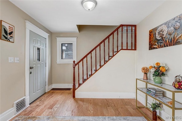 foyer entrance featuring stairs, wood finished floors, and baseboards
