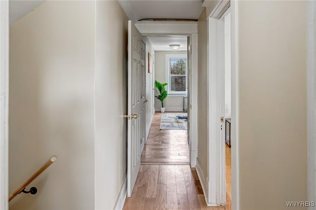 hallway featuring light wood-style floors, an upstairs landing, and baseboards