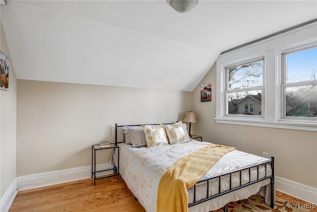 bedroom featuring lofted ceiling, wood finished floors, and baseboards
