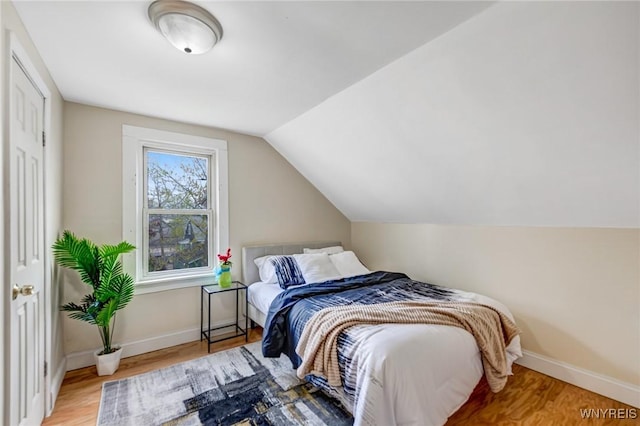 bedroom with wood finished floors, baseboards, and vaulted ceiling