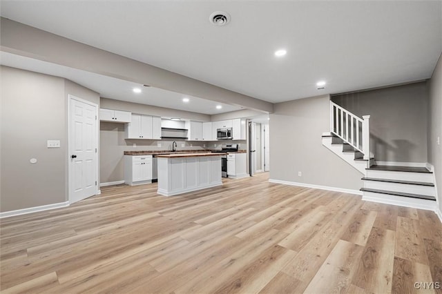 614 E Broadway St, Fulton, NY 13069 - kitchen with appliances with stainless steel finishes, open floor plan, white cabinetry, light wood-style flooring, and recessed lighting