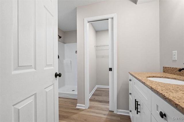 614 E Broadway St, Fulton, NY 13069 - bathroom with a shower stall, wood finished floors, a walk in closet, vanity, and baseboards