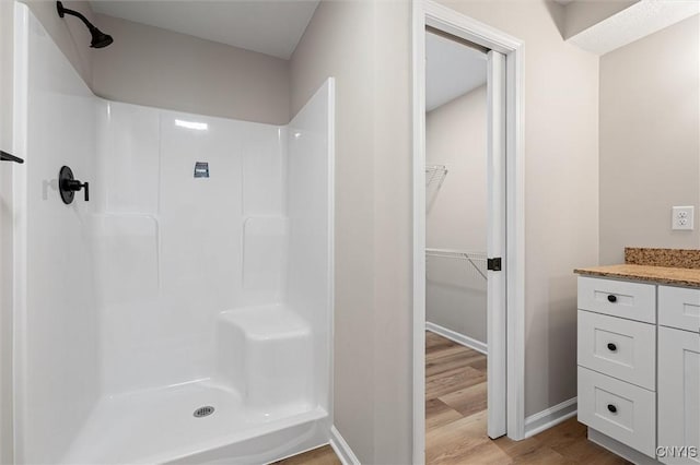 614 E Broadway St, Fulton, NY 13069 - full bathroom featuring wood finished floors, a shower, a walk in closet, and vanity