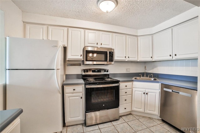 kitchen featuring appliances with stainless steel finishes, a sink, a textured ceiling, and white cabinetry